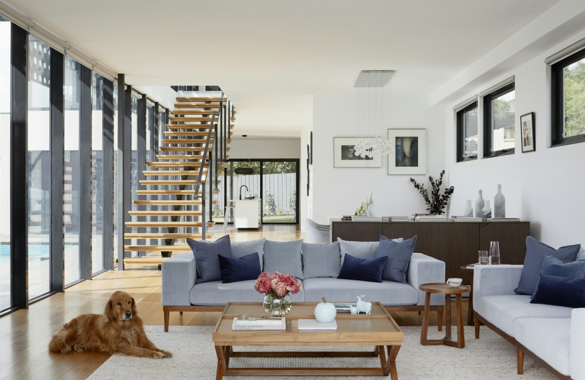 Sunlit living room with natural wood, comfortable seating, and an open staircase