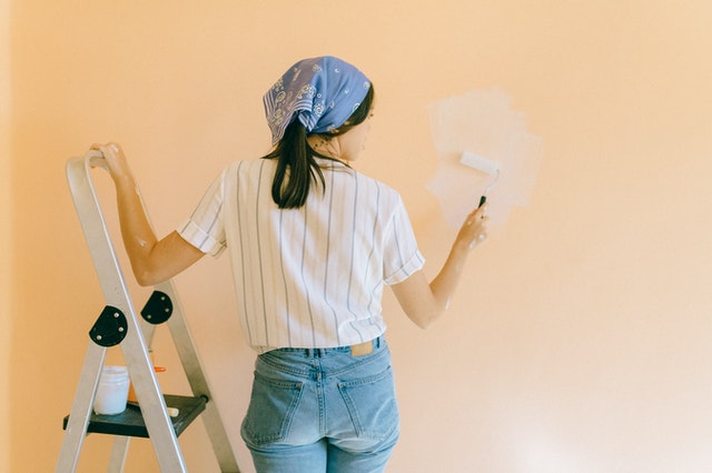 Woman improving her rented home by painting the walls.