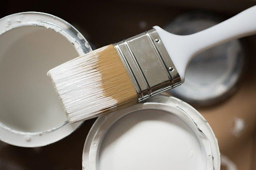White paint and a paintbrush for repainting home improvements