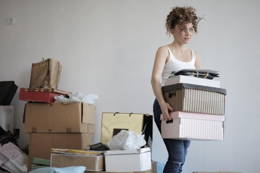 A woman carrying boxes to declutter and organize before a home remodel