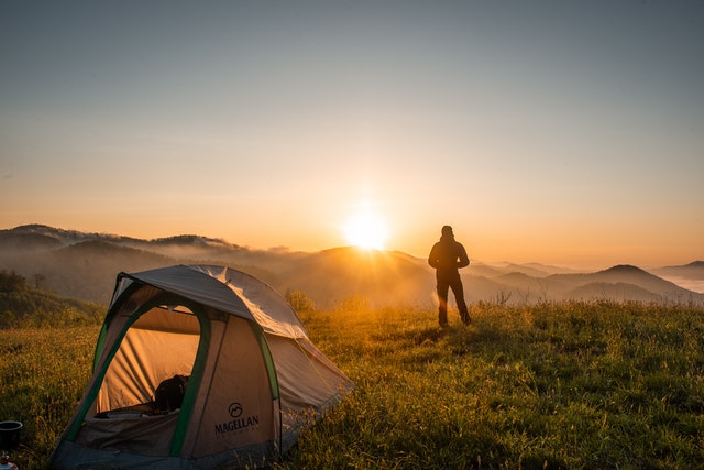  a camper standing beside a tent