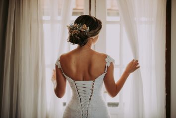 a women wearing a corset wedding dress looking out a window