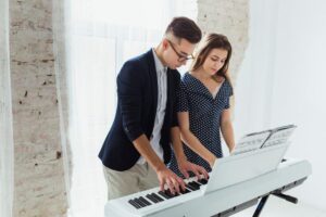 young-couple-standing-near-white-curtain-playing-piano_