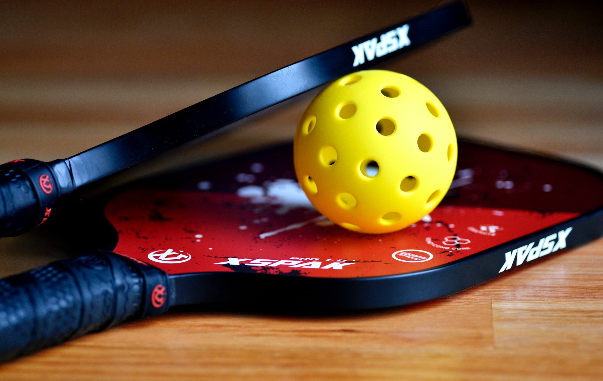 Two pickleball paddles and a yellow ball.
