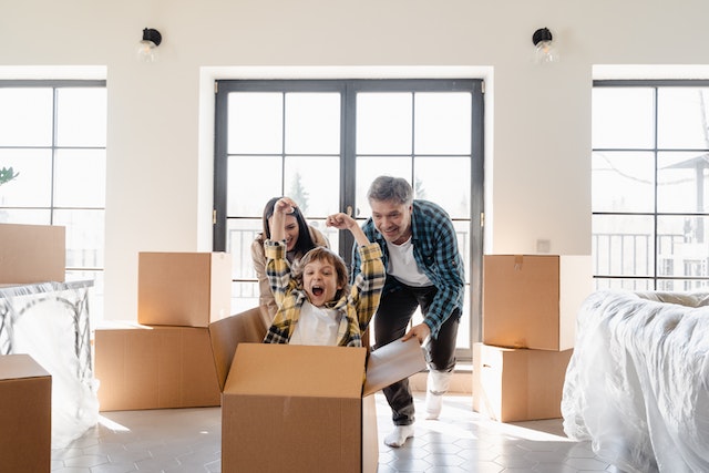 A couple playing with their kid and boxes in their new house