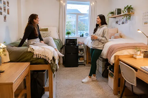 two girls in a college dorm room chit chatting