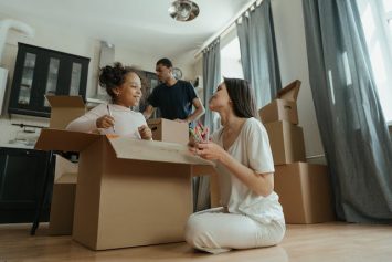 Family of three drawing and playing with boxes while unpacking as an example of turning the stress of relocation into an adventure