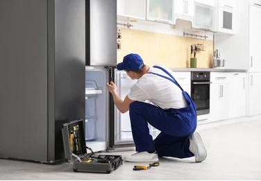 Male technician screw driving the refrigerator 