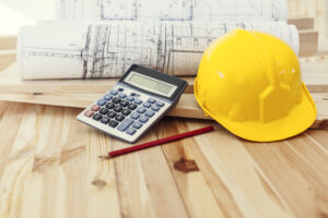 yellow-helmet-with-blueprints-calculator-wood-scaled